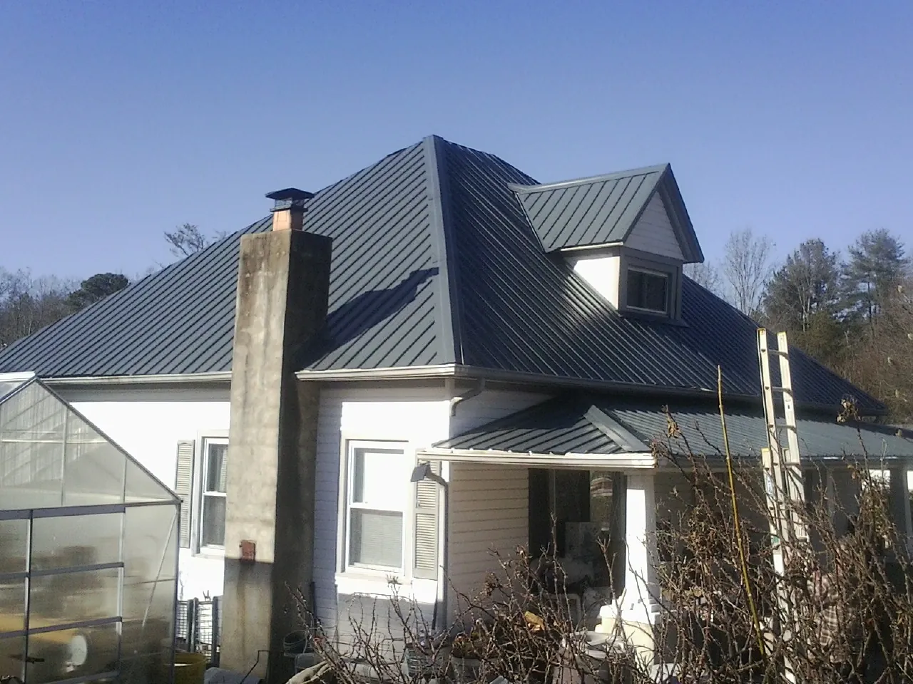 Dark blue standing seam metal roof on a white farmhouse with dormer — Slate & Tile Roof Repair by Roofing Brothers in Loudonville