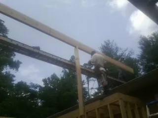 Carpenter setting a ridge beam over a new addition frame — Ice Dam Removal by Roofing Brothers in Loudonville