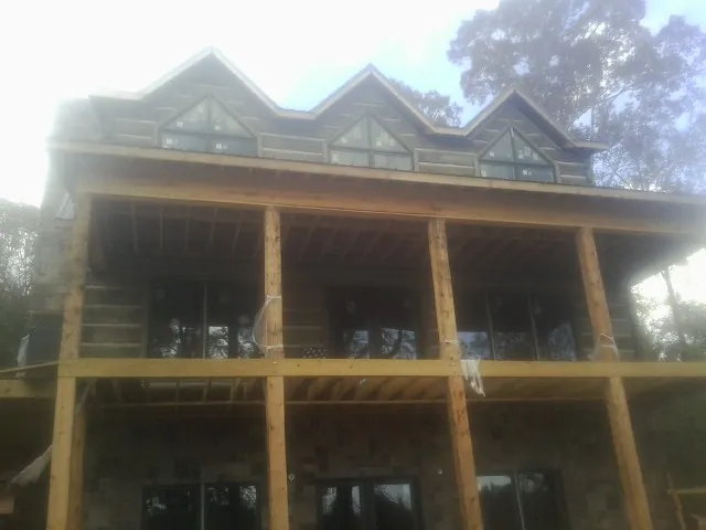 Dormers and porch framing on a large log home under construction — Roof Coating work by our crew in Loudonville