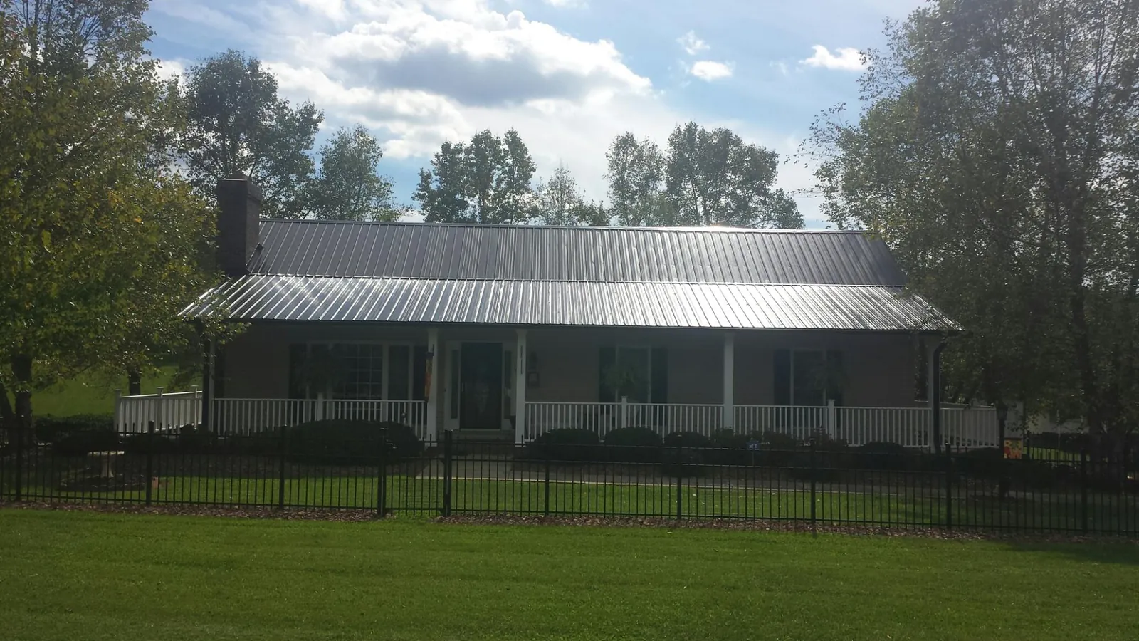 Gray metal roof on a brick ranch with a full width front porch — Gutter Guard Installation work by our crew in Loudonville
